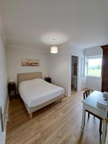 a bedroom with a white bed and a table at Ferme Auberge Ibarnia in Lecumberry