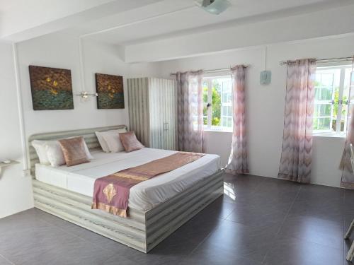 a bedroom with a bed and two windows at Le Beau Manguier Residence in Pereybere