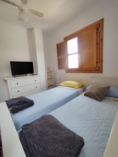een slaapkamer met 2 bedden, een tv en een raam bij El mirador del beregenal in Enix