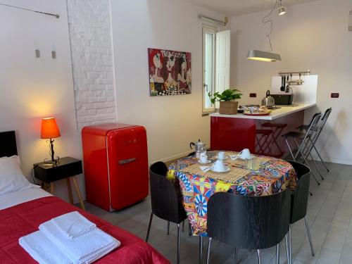 um quarto com uma mesa e uma cozinha com um frigorífico vermelho em Guest house Le Sibille em Taormina