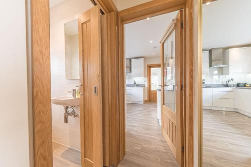 a kitchen with white cabinets and a sink at Cherry Garth HOT TUB HIRE AVAILABLE in Keswick