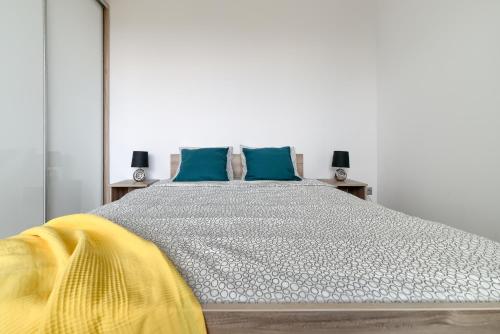 a bedroom with a large bed with blue pillows at Gris Apartment in Poznań