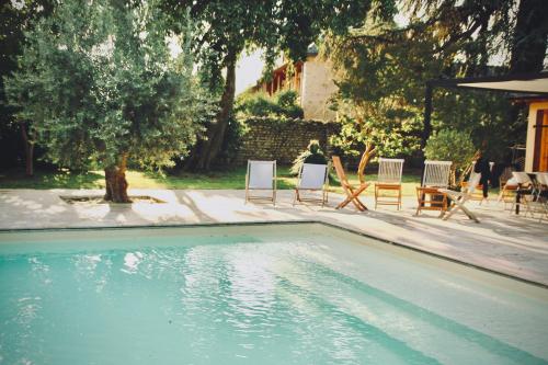a swimming pool in a yard with chairs and tables at Le Moulin du Château de Horgues in Horgues