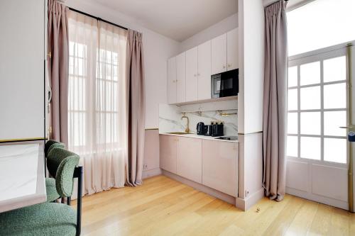 - une cuisine avec des placards blancs et des fenêtres dans une pièce dans l'établissement Pick A Flat's Apartment in Place Vendôme - Rue Duphot, à Paris