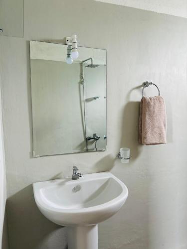 a white bathroom with a sink and a mirror at One Bhakthi in Ahangama