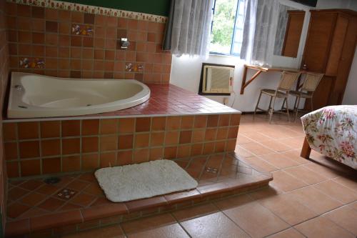 a bathroom with a tub in a tiled floor at Pousada 3 Corações in Penedo