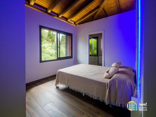 ein Schlafzimmer mit lila Wänden und ein Bett mit einem Fenster in der Unterkunft Casa Ananda in Palamós