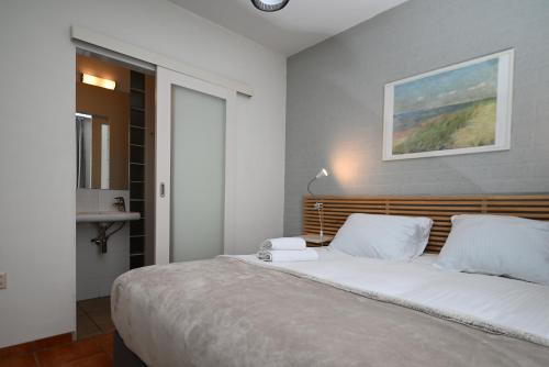 ein Schlafzimmer mit einem großen Bett mit weißen Kissen in der Unterkunft The Green Studio, Lopinge 94 in Cadzand