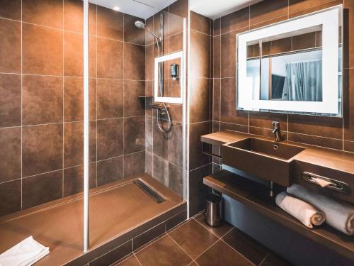 a bathroom with a sink and a shower at Novotel Lens Noyelles in Noyelles-Godault