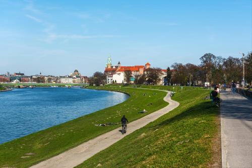 a person riding a bike on a path next to a river at Heart of Cracow in Krakow