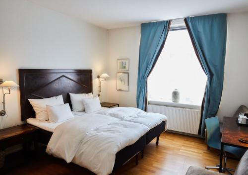 a bedroom with a large bed with a large window at Hotel Kong Arthur in Copenhagen