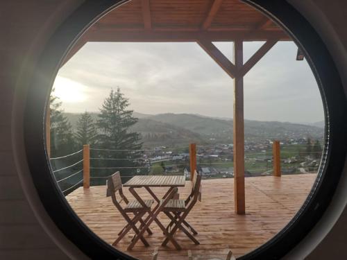 a table and chairs on a deck with a view at Fancy Maisonnette in Gura Humorului