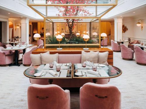 un restaurant avec des chaises roses et une table dans une pièce dans l'établissement Sofitel Le Scribe Paris Opera, à Paris