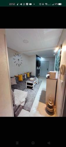 a living room with a couch and a clock on the wall at appartement résidence dchaira jadida in Dcheira El Jihadia