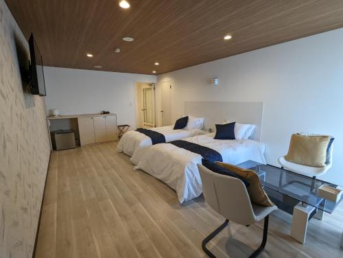 松山市にある瀬戸内リゾートホテルのベッド2台とガラスのテーブルが備わるホテルルームです。