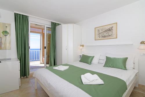 a bedroom with a large bed with green and white pillows at Kate's Place in Dubrovnik