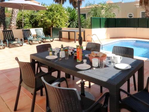 聖巴巴拉德尼克斯的住宿－Holiday Home Quinta da Fonte - SBN201 by Interhome，一张黑桌和椅子,旁边是游泳池
