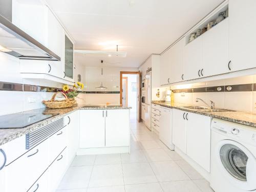 a kitchen with white cabinets and a washer and dryer at Holiday Home Santiago - RDB100 by Interhome in Roda de Bará