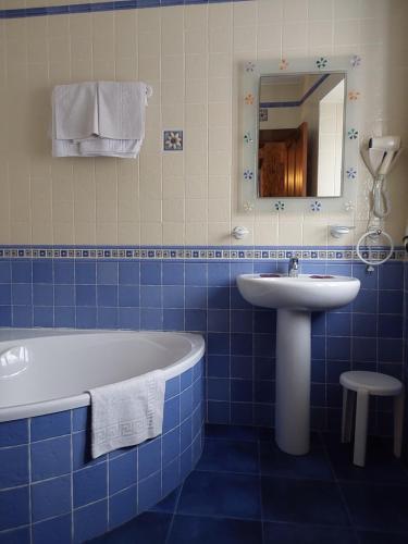 baño de azulejos azules con bañera y lavamanos en POSADA LAS MOZAS DEL AGUA DE GABY Y TINO, en Ríocorvo