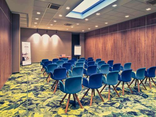 a conference room with blue chairs and a podium at Mercure Jelenia Góra in Jelenia Góra
