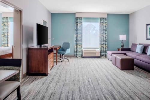 a hotel room with a couch and a desk and a tv at Hilton Garden Inn Charleston / Mt. Pleasant in Charleston