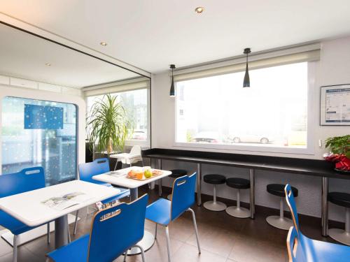 a restaurant with blue chairs and tables and a window at Ibis Budget Bilbao Arrigorriaga in Arrigorriaga
