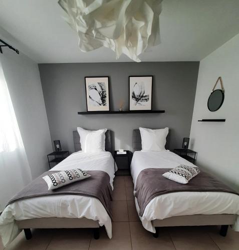 une chambre avec deux lits avec des oreillers dessus dans l'établissement L'Ajolan Genas/Eurexpo/Groupama Stadium/ Lyon St Exypéry, à Genas