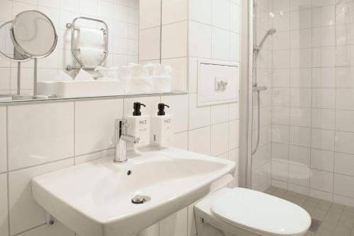 a white bathroom with a sink and a toilet at Scandic Malmö City in Malmö