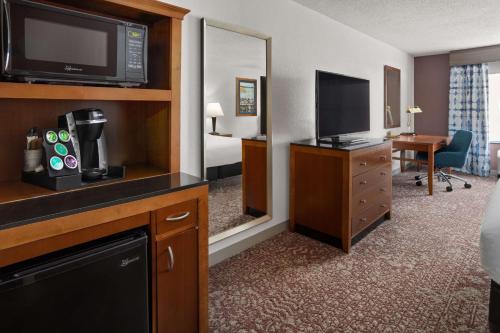 a hotel room with a television and a bedroom at Hilton Garden Inn Milford in Milford