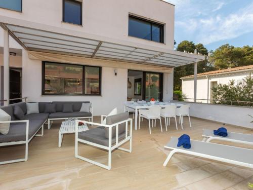 a patio with white furniture and a table and chairs at Holiday Home Sa Riera White on the Beach by Interhome in Begur