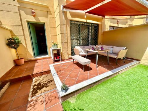un patio con una mesa y sillas en el césped en GATU PREMIUM Villa Sal Marina "preferente para mayores de 25 años y familias ", en El Puerto de Santa María