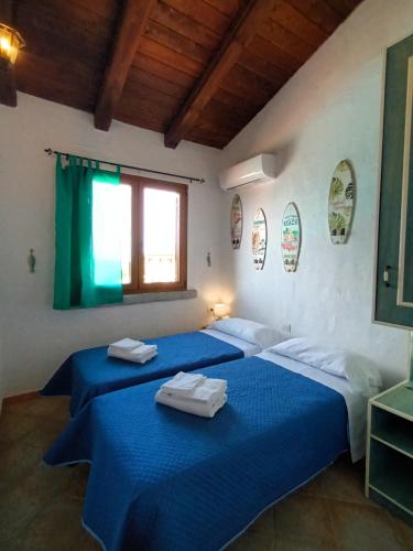 two beds in a room with blue sheets at Il Miraggio Tanca Piras in Nebida