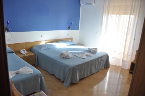 two beds in a hotel room with towels on them at Hotel Le Pelagie in Lampedusa