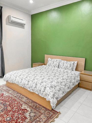 a bedroom with a bed with a green wall at Cahaya Melissa Homestay Private Pool in Melaka