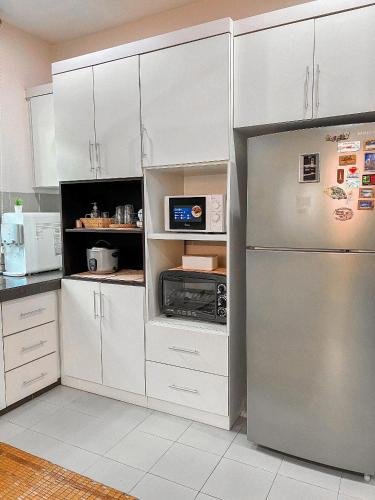 a kitchen with white cabinets and a stainless steel refrigerator at Cahaya Melissa Homestay Private Pool in Melaka