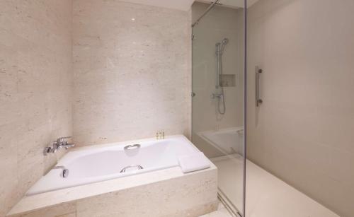 a white bathroom with a tub and a shower at Hilton Garden Inn Hong Kong Mongkok in Hong Kong