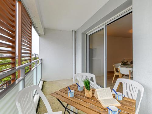 d'un balcon avec une table en bois et des chaises blanches. dans l'établissement Apartment Clos Telenn by Interhome, à Carnac