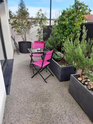 un patio avec des chaises roses et des plantes en pot dans l'établissement L'Ajolan Genas/Eurexpo/Groupama Stadium/ Lyon St Exypéry, à Genas