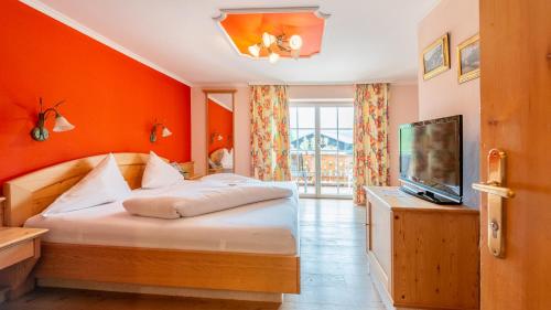 een slaapkamer met een bed met een oranje muur bij Hotel Försterhof lebe pur, genieße den Tag in St. Wolfgang