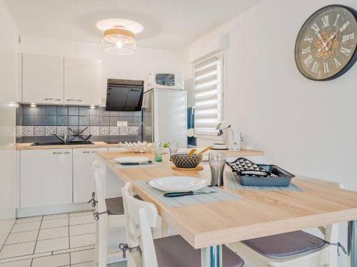 Apartment Les Caps Horniers-2 by Interhome في Pleurtuit: مطبخ مع طاولة خشبية وساعة على الحائط