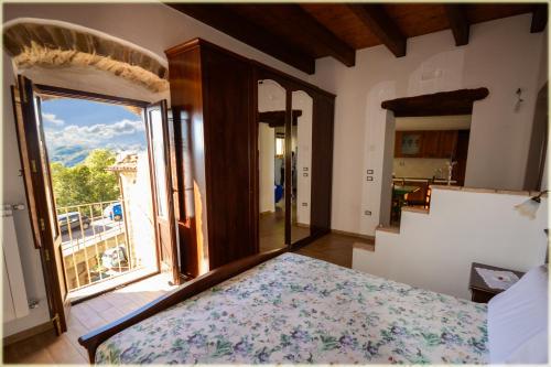 ein Schlafzimmer mit einem Bett und einem großen Fenster in der Unterkunft Il Palazzo del Barone - Dimora storica in Pietrapertosa