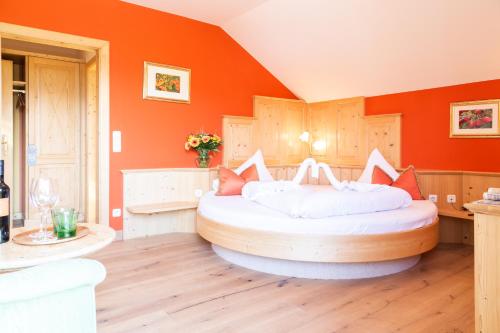 ein Schlafzimmer mit einem großen Bett und einer orangefarbenen Wand in der Unterkunft Hotel Försterhof lebe pur, genieße den Tag in St. Wolfgang