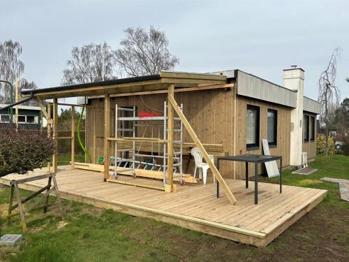 a tiny house with a porch and a playground at Holiday Home Tedora - all inclusive - 250m from the sea by Interhome in Odder