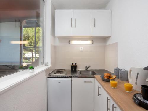 une cuisine avec des placards blancs et une plaque de cuisson sur un comptoir dans l'établissement Studio Les Marquises by Interhome, à La Grande Motte