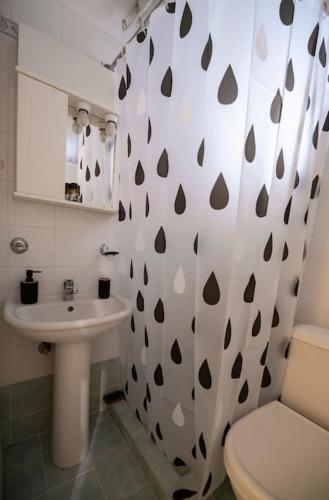 a bathroom with a sink and a toilet and a shower curtain at Μάνια in Pythagoreio