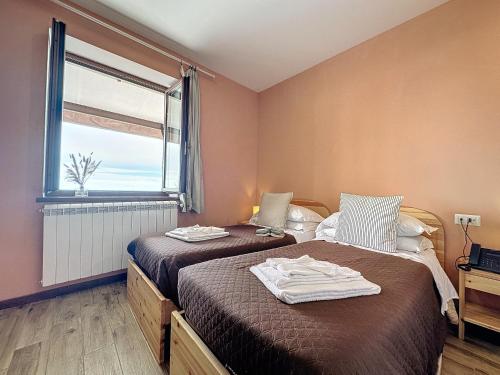2 Betten in einem Zimmer mit Fenster in der Unterkunft Albergo Rifugio La Grande Baita in Cutigliano