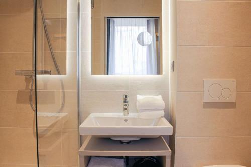 een badkamer met een wastafel en een douche bij Brit Hotel Limoges Centre Gare - Hôtel & Spa in Limoges
