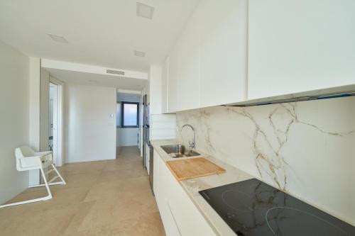 a kitchen with white cabinets and marble counter tops at Casa Marc in San José