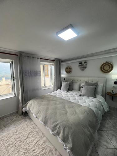 a bedroom with a large bed and two windows at Himalayas in Gjirokastër