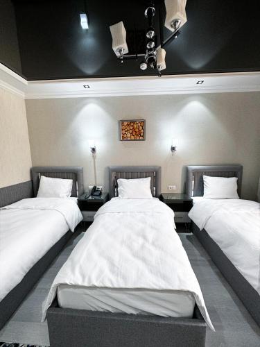 two beds in a room with white sheets at De Villa Hotel in Samarkand